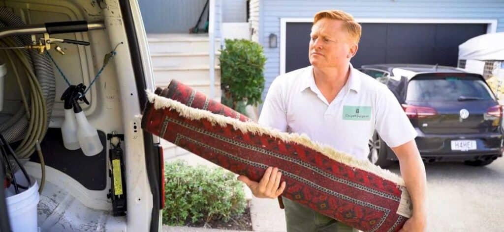 carpet specialist loading rug into vehicle